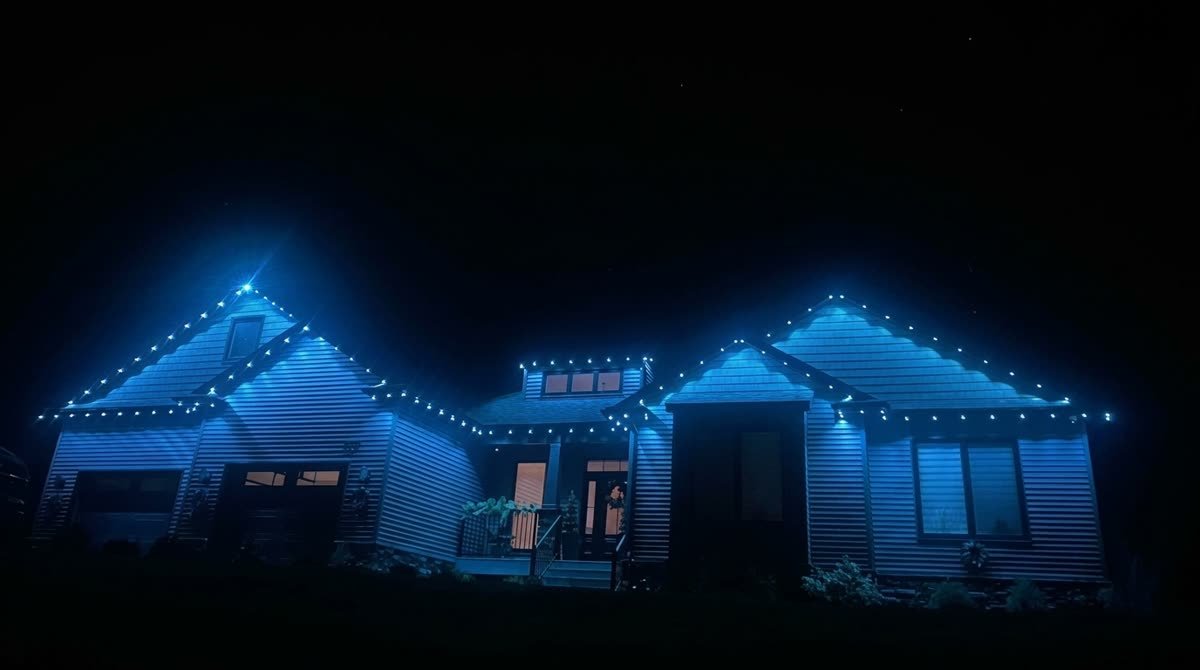 Two-storey home traced in cool blue permanent lighting along every roofline at night